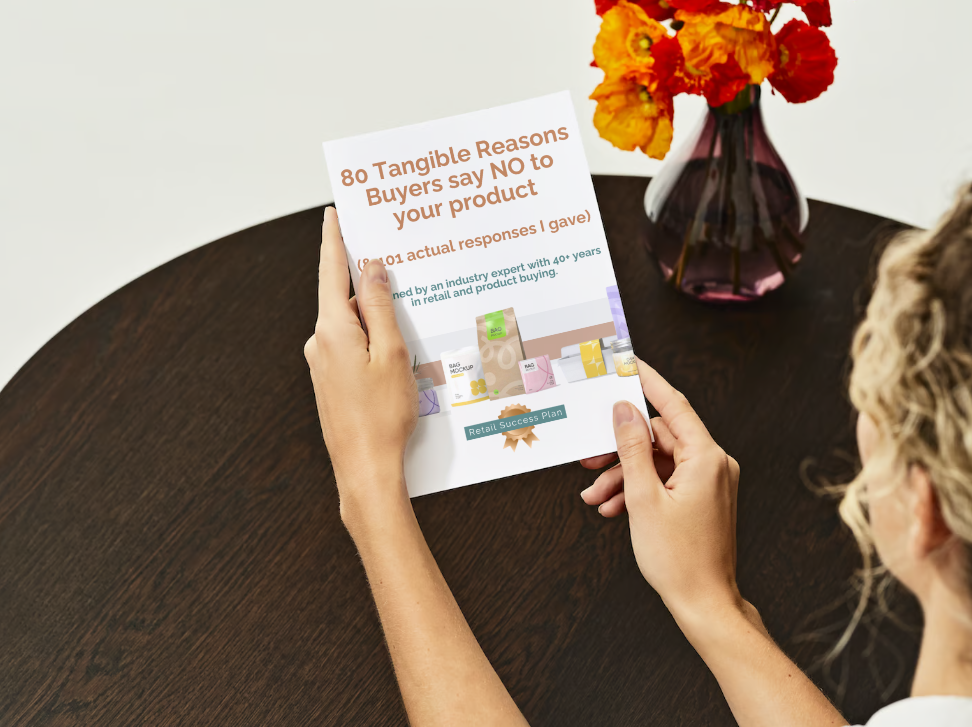 A woman holding a book titled 80 Tangible Reasons Buyers say NO to your product (and 101 actual responses I gave)